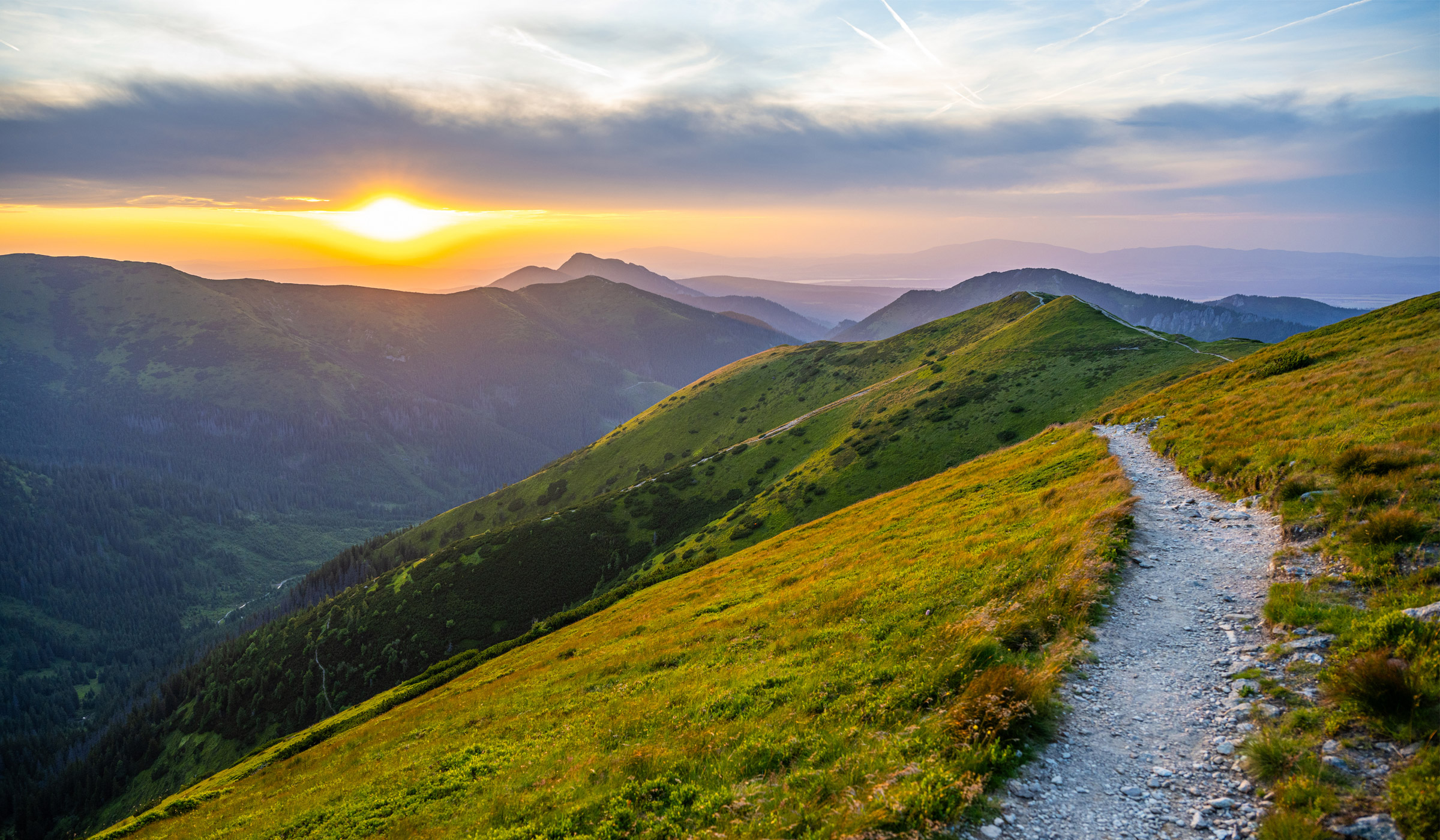 Sunset over green mountain trail