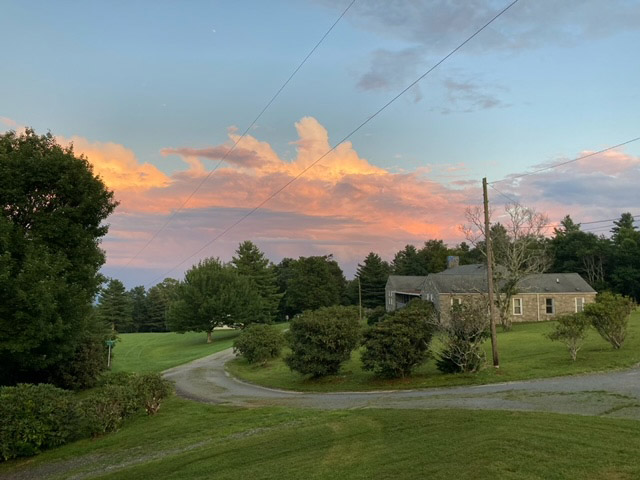 Countryside at sunset with house and vibrant sky.