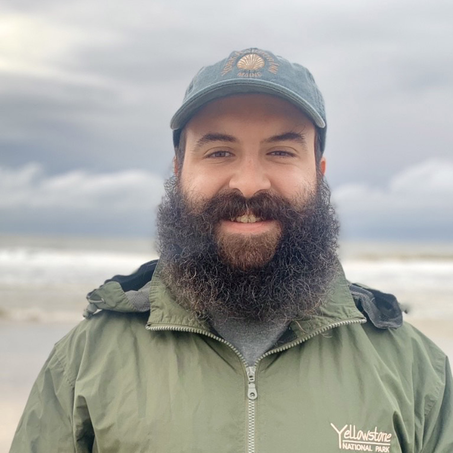 Man with beard smiling on a cloudy beach