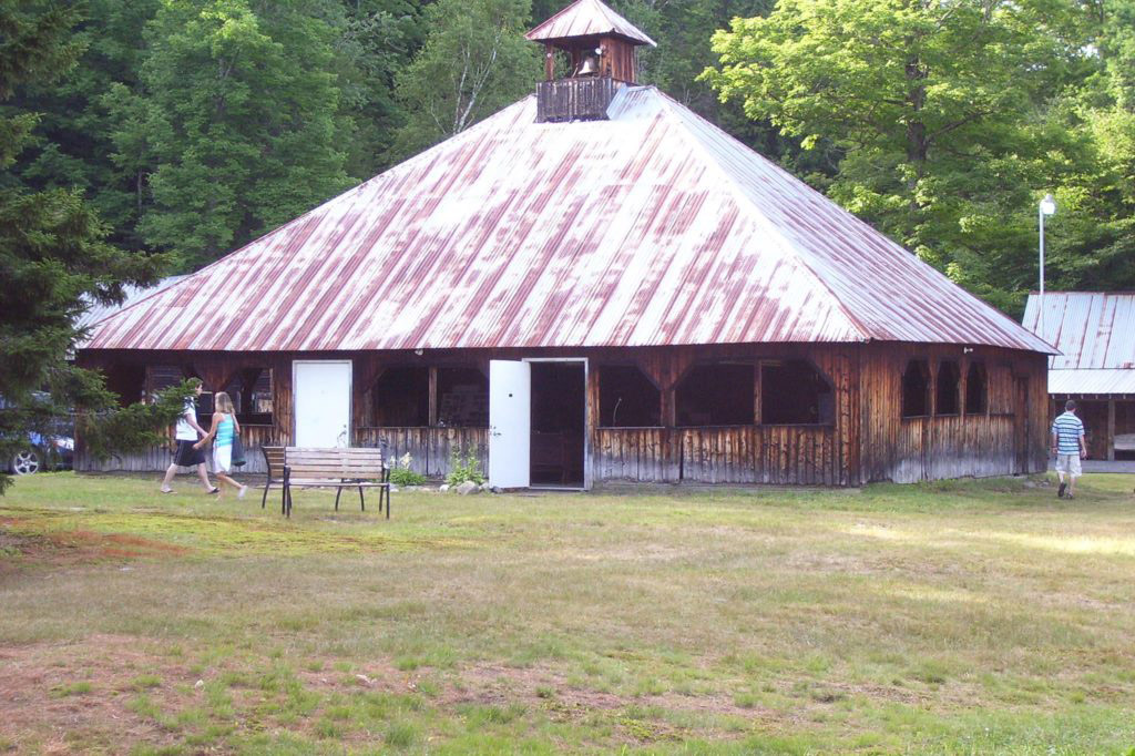 Rustic building with metal roof in forest clearing.