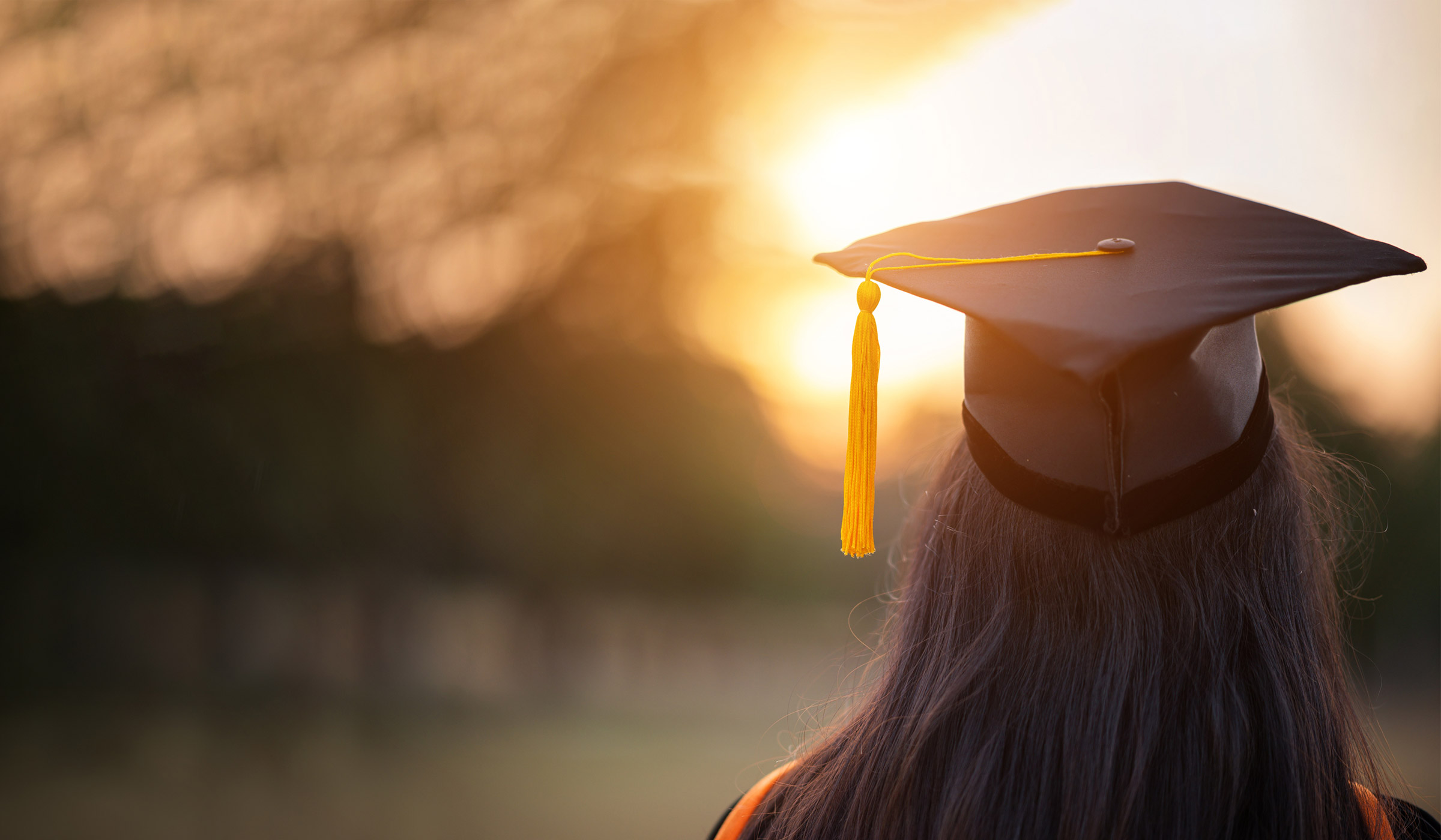 Graduate in cap watching sunset