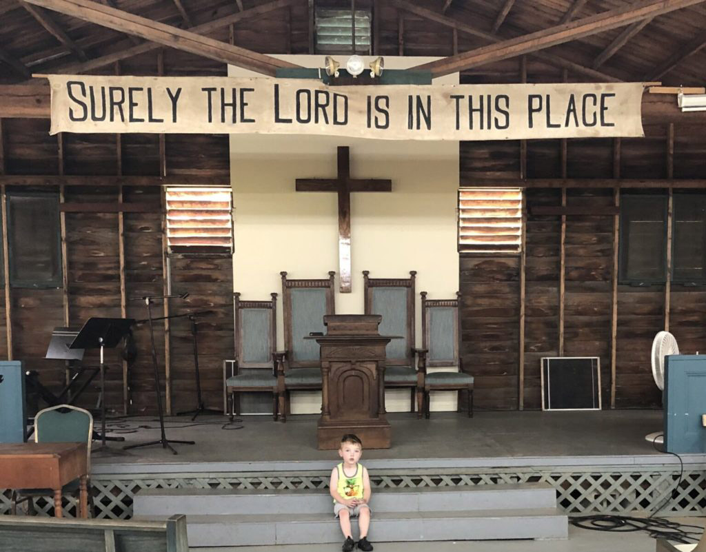 Child sits in front of church altar and banner.