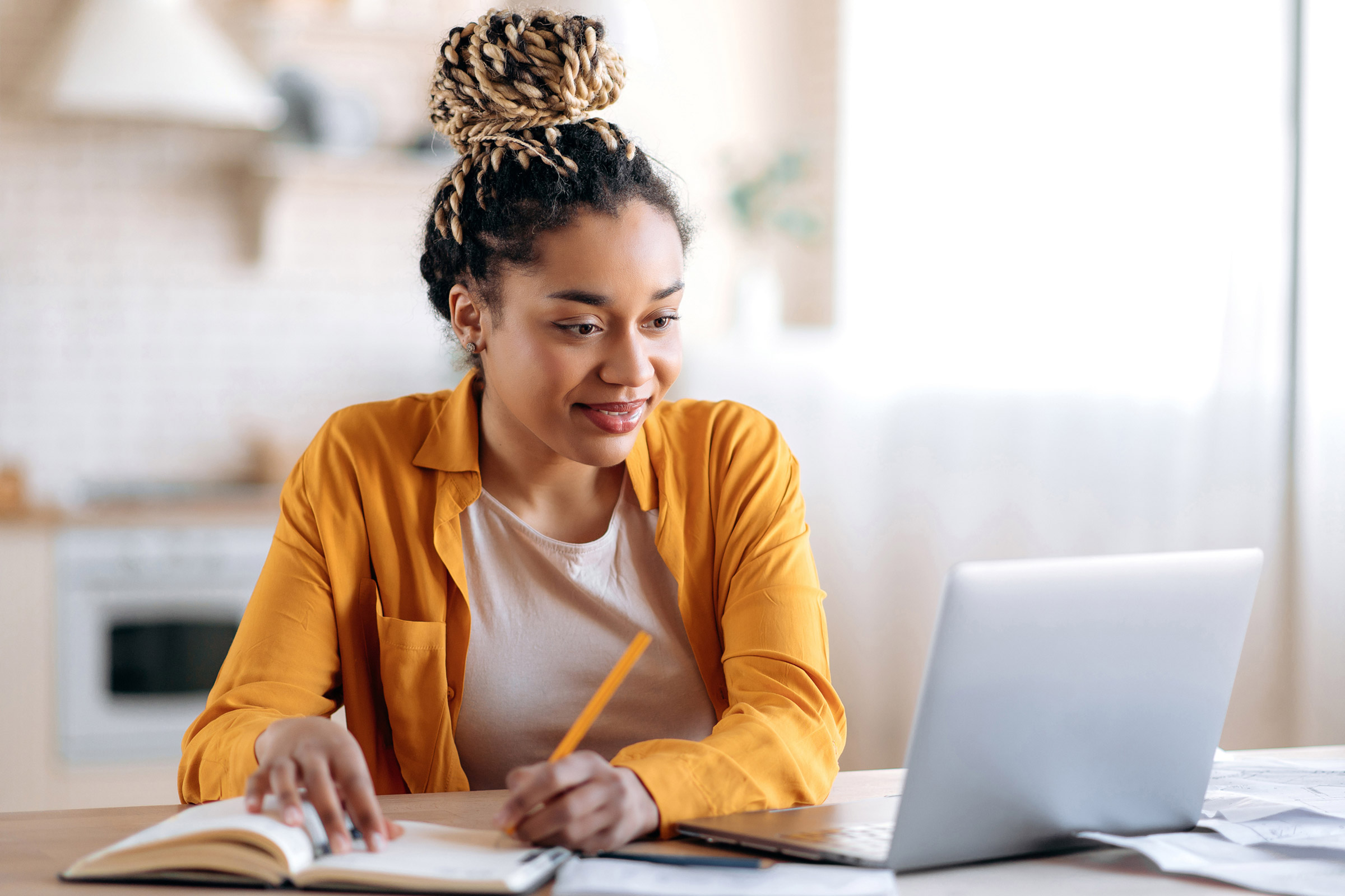 Woman working on laptop and writing notes