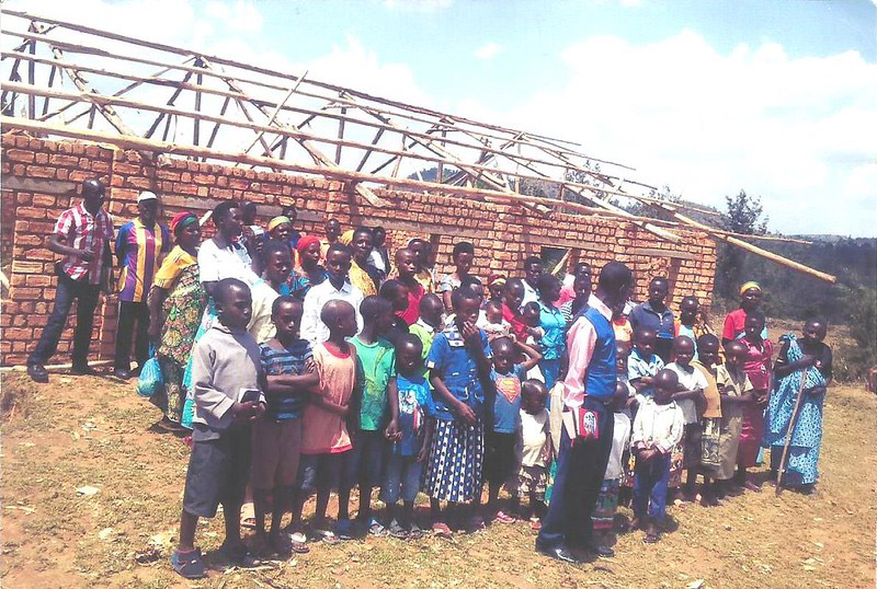 Group of people in front of brick building construction.