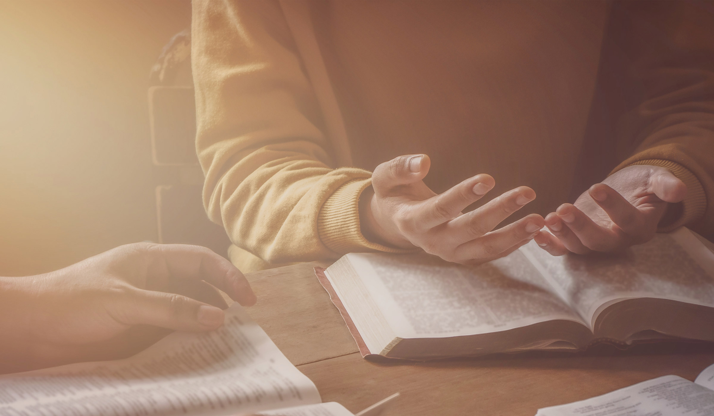 Hands gesturing above open book on table.