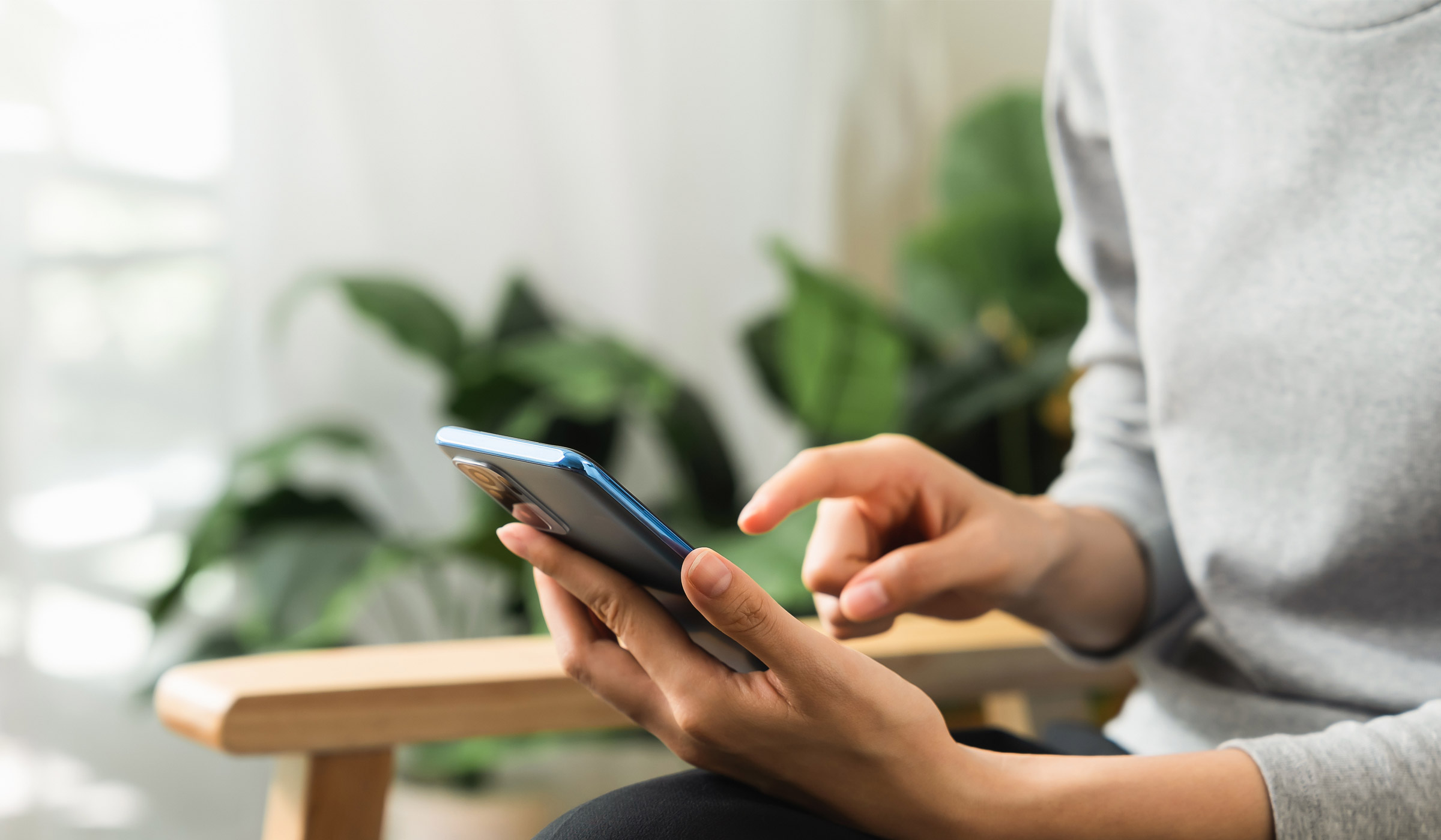 Person using smartphone indoors near plants